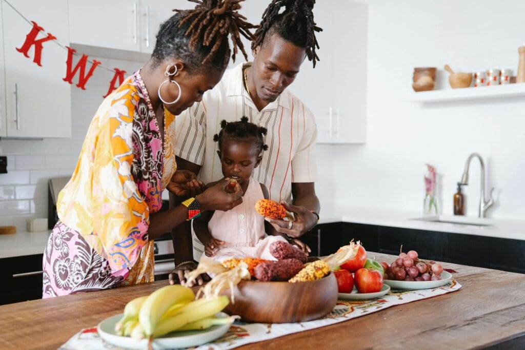 Família reunida na cozinha, mãe, pai e filha, comendo frutas