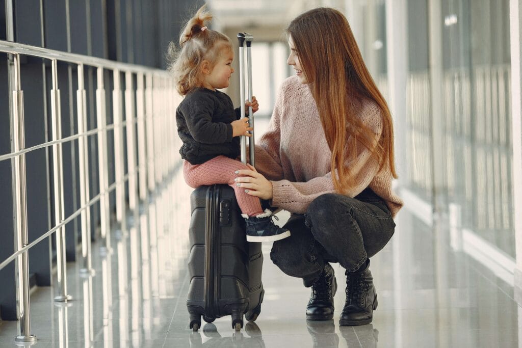 mãe e filha sentada na mala, esperando no aeroporto