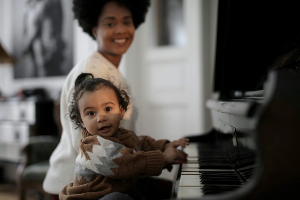 pexels-olly-3818520 (1) criança tocando piano ao lado de sua mãe. Beneficios da música para bebês