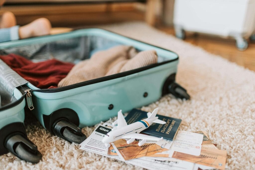 Documentos para viajar com crianças, passaporte e mala aberta no chão